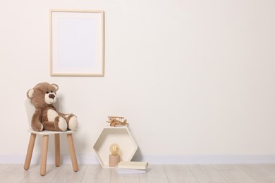 Photo of Beautiful children's room with light wall, furniture and toys, space for text. Interior design