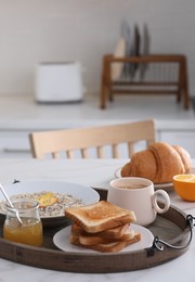 Photo of Wooden tray with delicious breakfast on table in kitchen, space for text