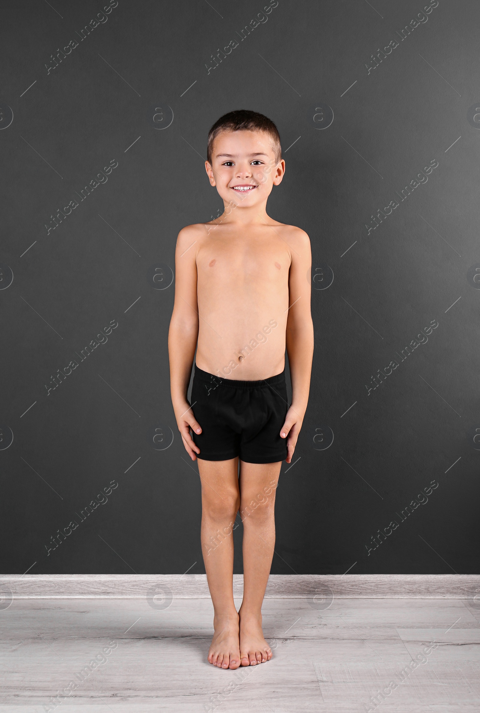 Photo of Cute little boy in underwear near dark wall