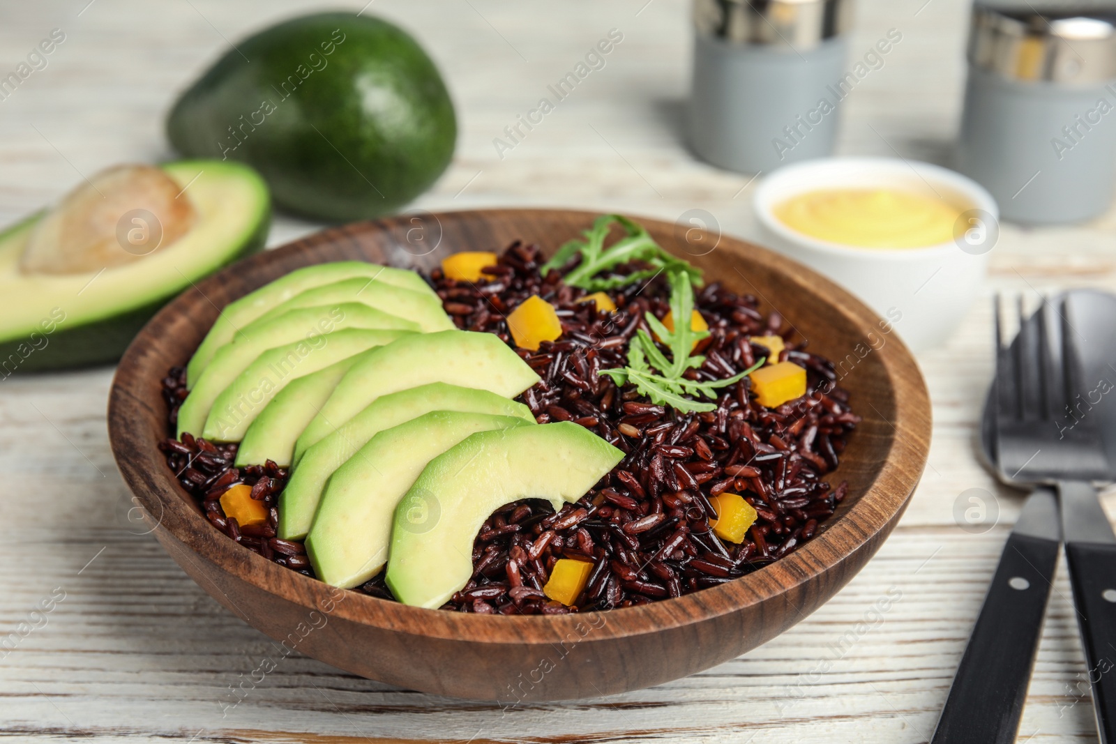 Photo of Bowl with delicious cooked brown rice on white wooden table