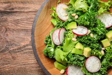 Photo of Delicious kale salad on wooden table, top view