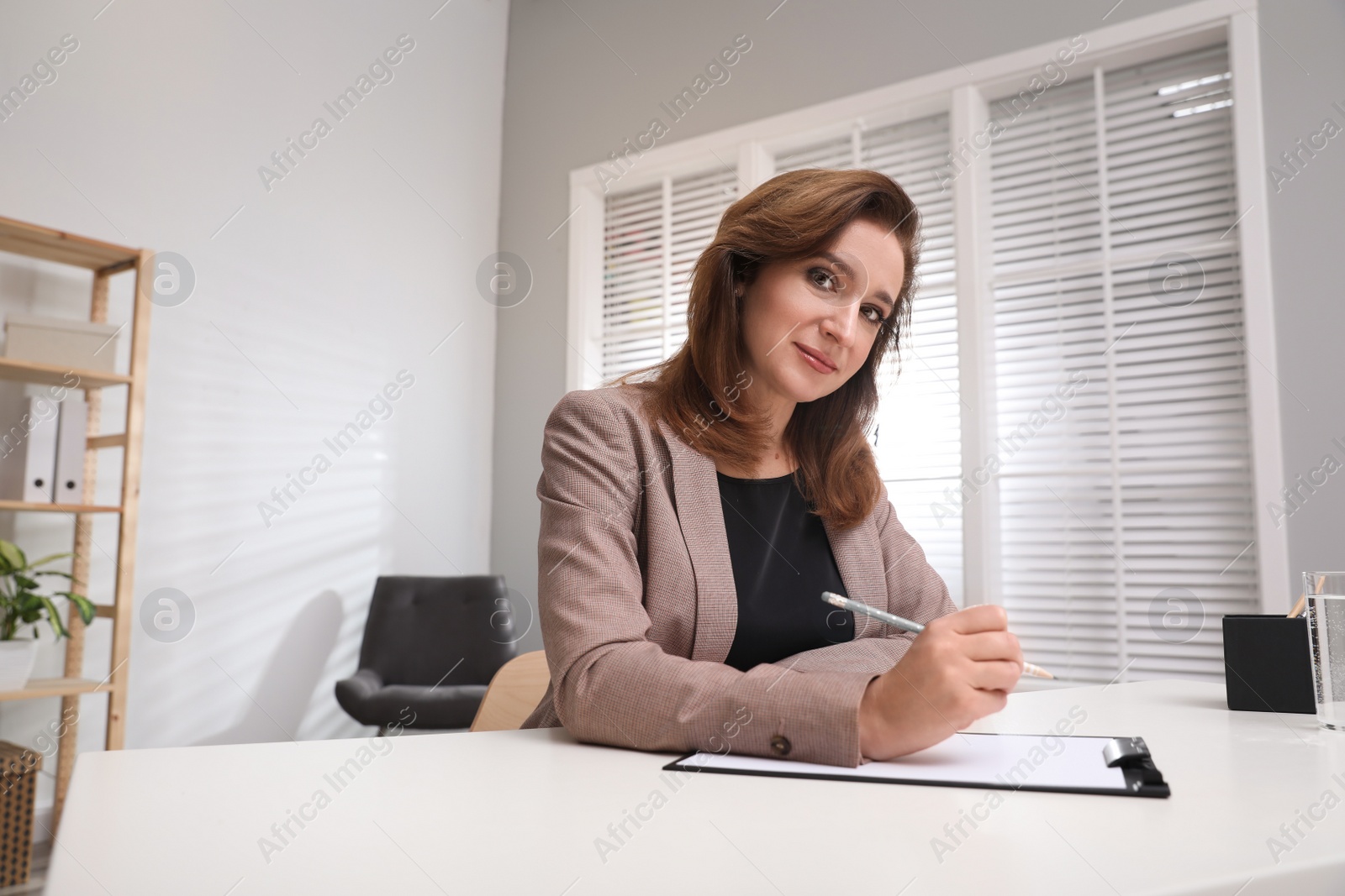 Photo of Portrait of psychotherapist with clipboard at table in office