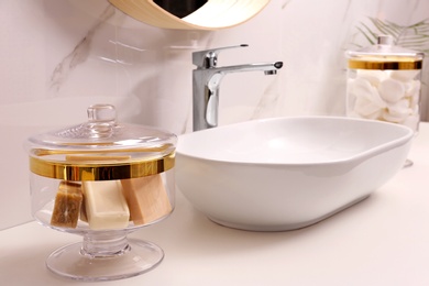 Photo of Glass jar with bars of soap on table in bathroom