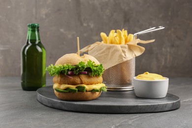 Photo of Tasty vegetarian burger served with french fries and beer on black table