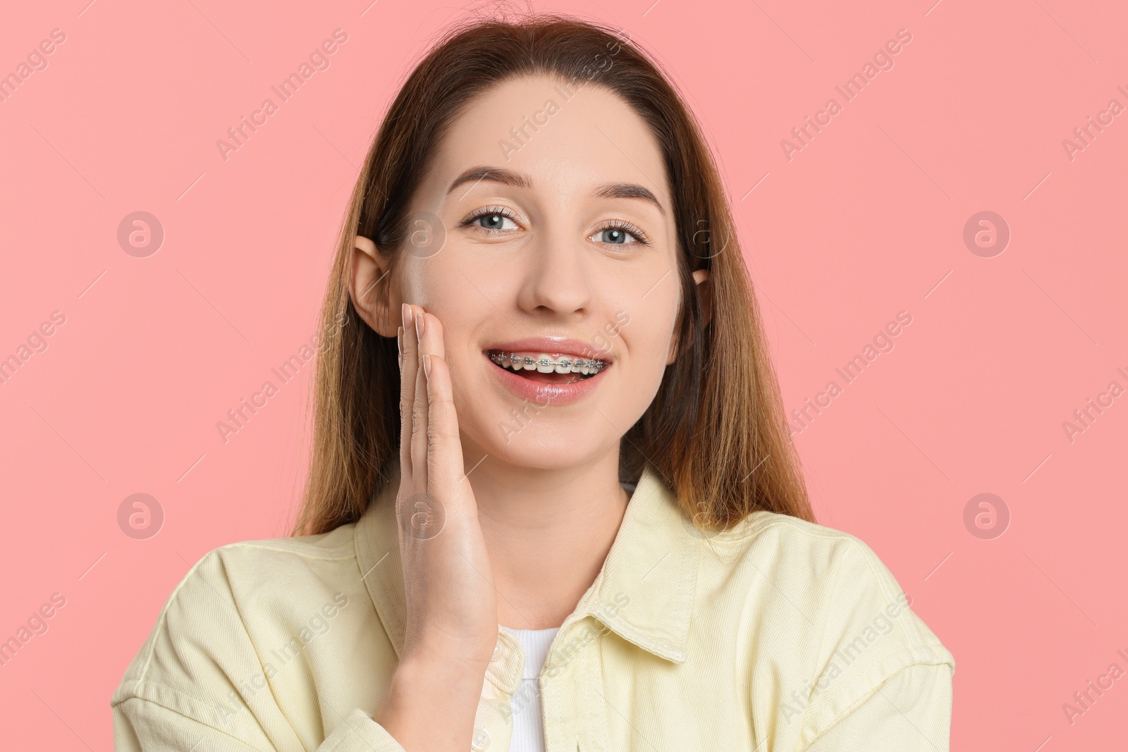 Photo of Portrait of smiling woman with dental braces on pink background
