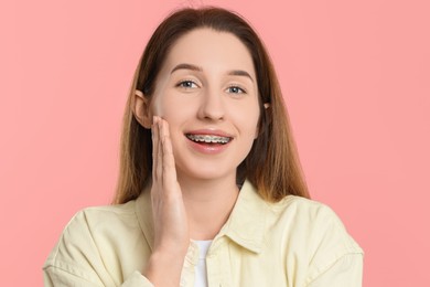 Portrait of smiling woman with dental braces on pink background