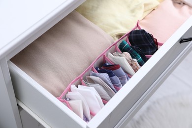Photo of Open drawer with folded handkerchiefs and clothes indoors, closeup
