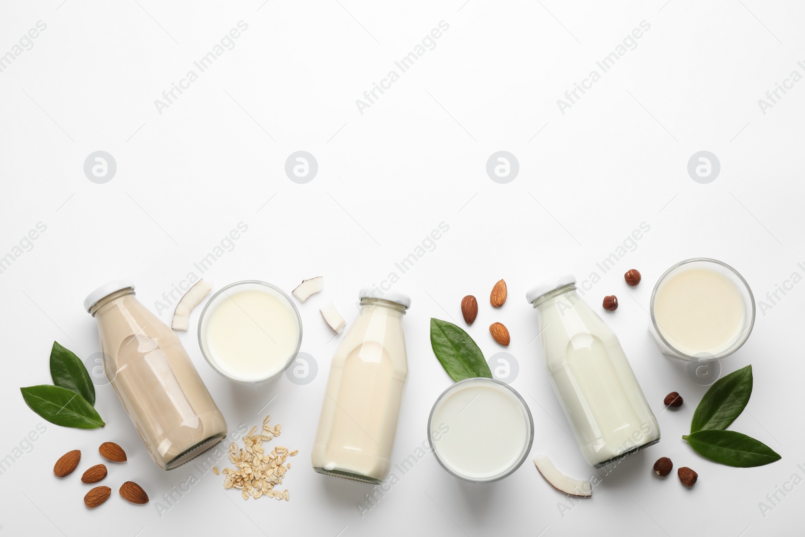 Photo of Different vegan milks and ingredients on white background, flat lay. Space for text