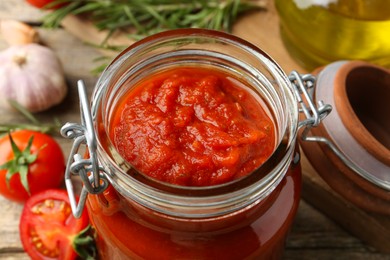 Photo of Homemade tomato sauce in jar on table, closeup