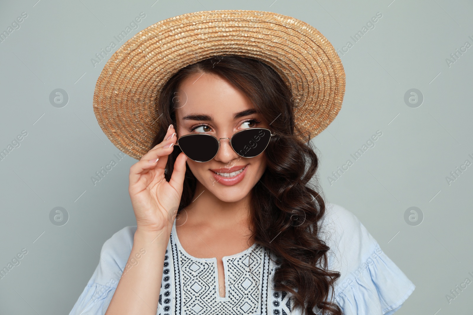 Photo of Beautiful young woman with straw hat and stylish sunglasses on light grey background