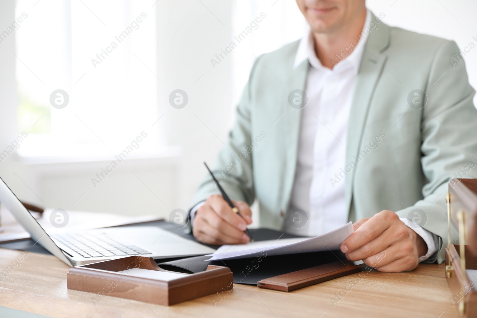 Photo of Male notary signing document at table in office, closeup