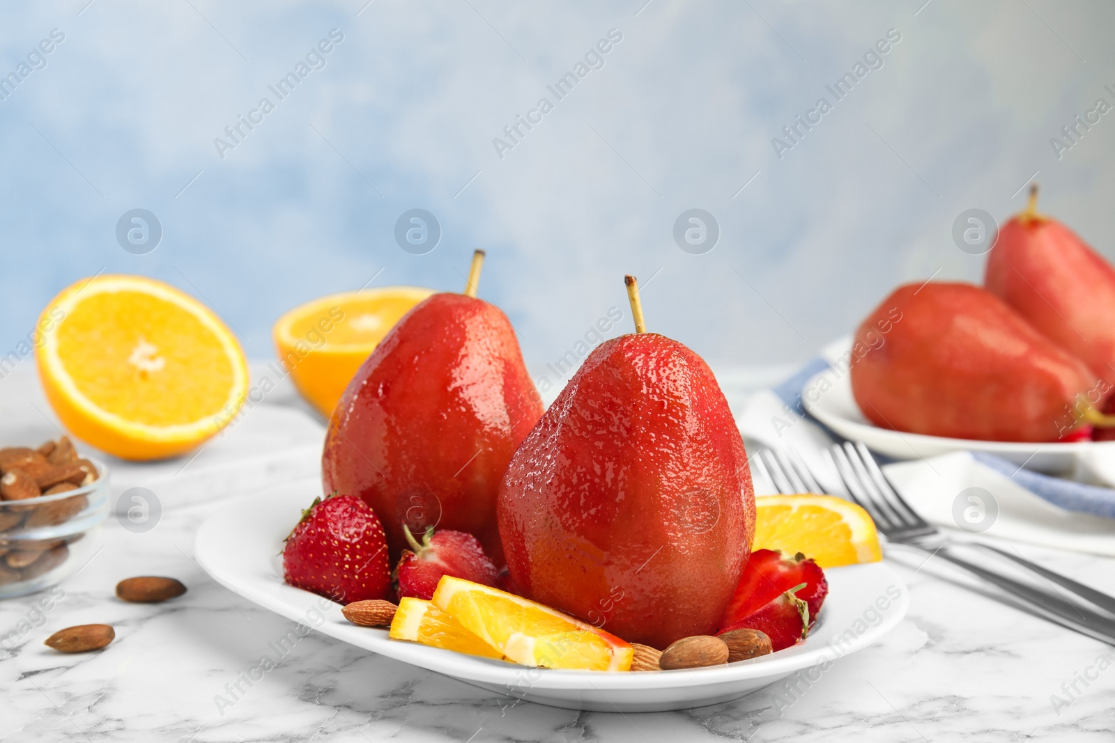 Photo of Plate with red wine poached pears and fruits on marble table