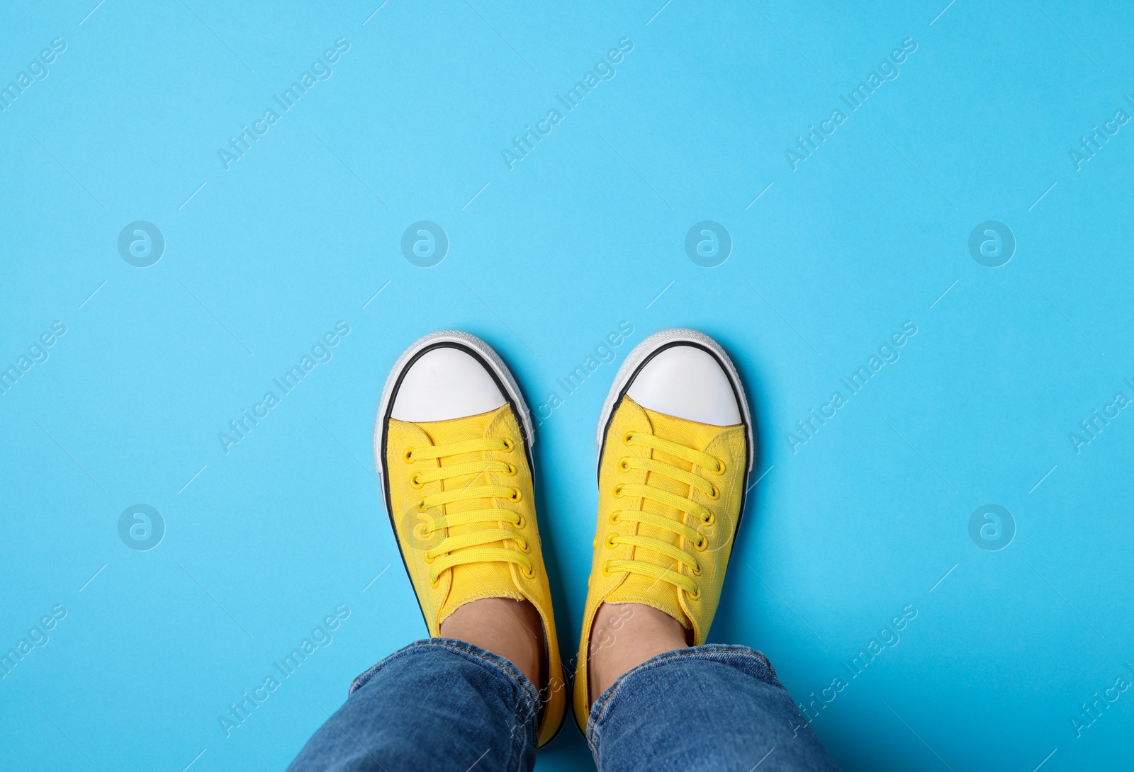 Photo of Woman in stylish gumshoes on light blue background, top view