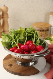 Photo of Wet radish in colander on white table, closeup