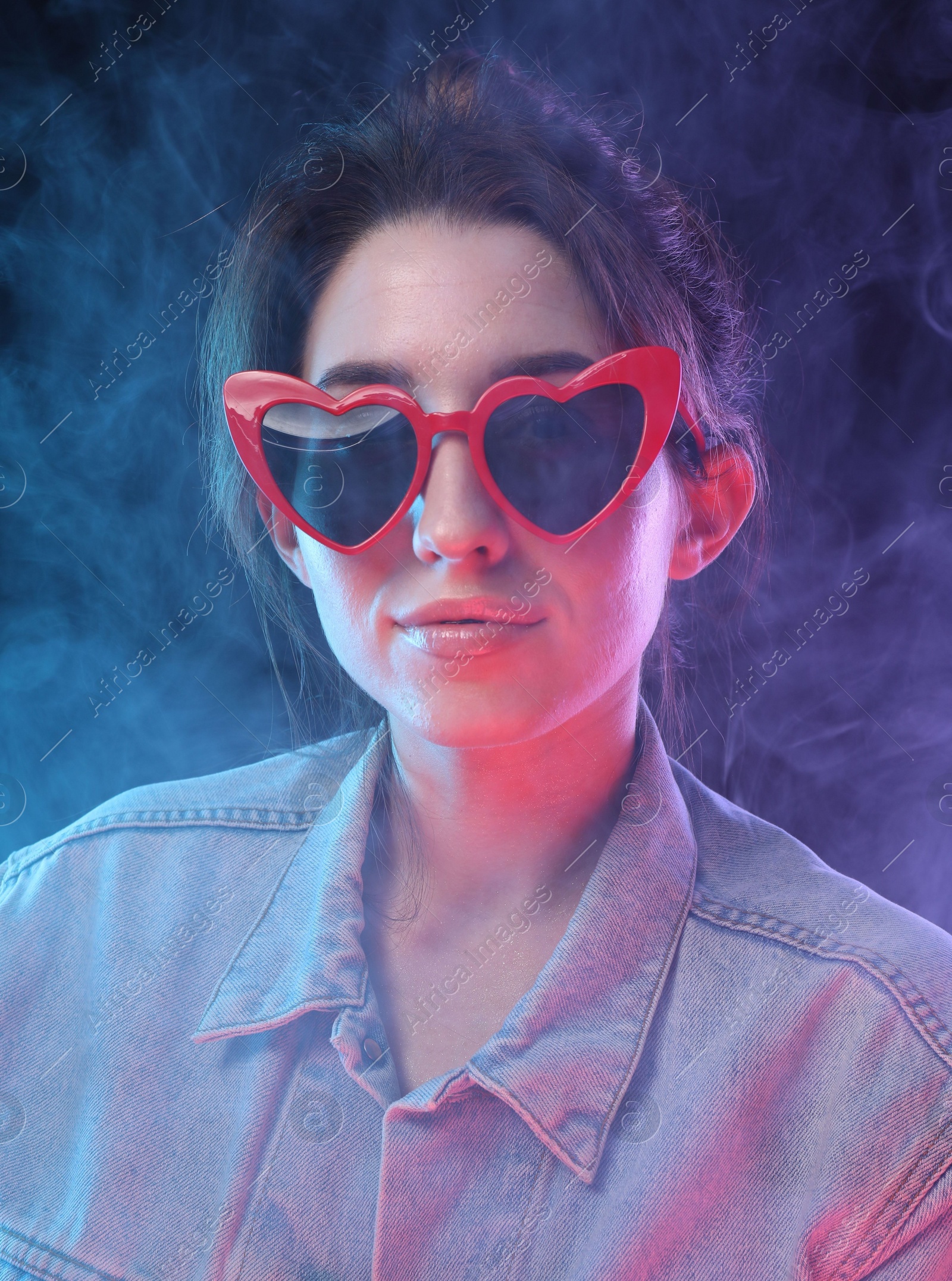 Photo of Young woman wearing sunglasses in smoke on color background