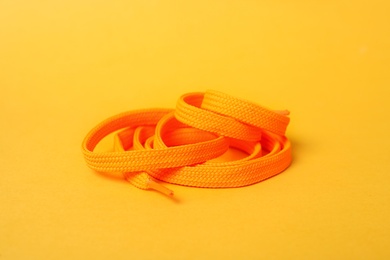 Photo of Orange shoe lace on yellow background. Stylish accessory