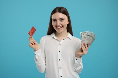 Happy woman with credit card and dollar banknotes on light blue background