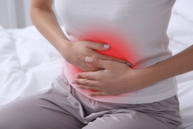 Image of Woman suffering from abdominal pain on bed, closeup