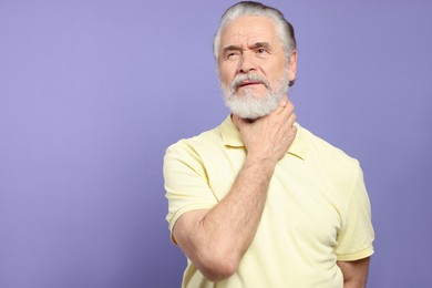 Senior man suffering from sore throat on light purple background, space for text. Cold symptoms