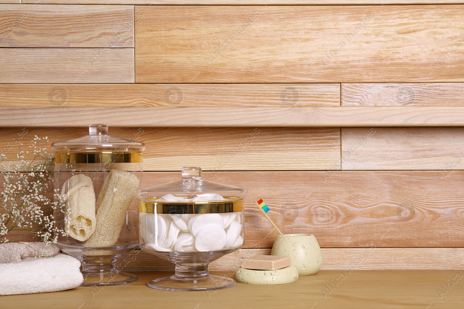 Photo of Composition of glass jar with cotton pads on table near wooden wall. Space for text