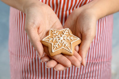 Photo of Woman holding tasty homemade Christmas cookie decorated with icing, closeup