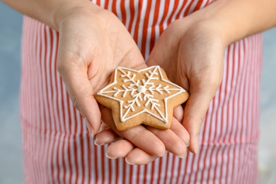 Woman holding tasty homemade Christmas cookie decorated with icing, closeup