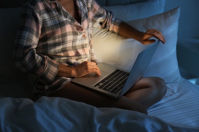 Woman using laptop in bed at night, closeup. Sleeping disorder problem