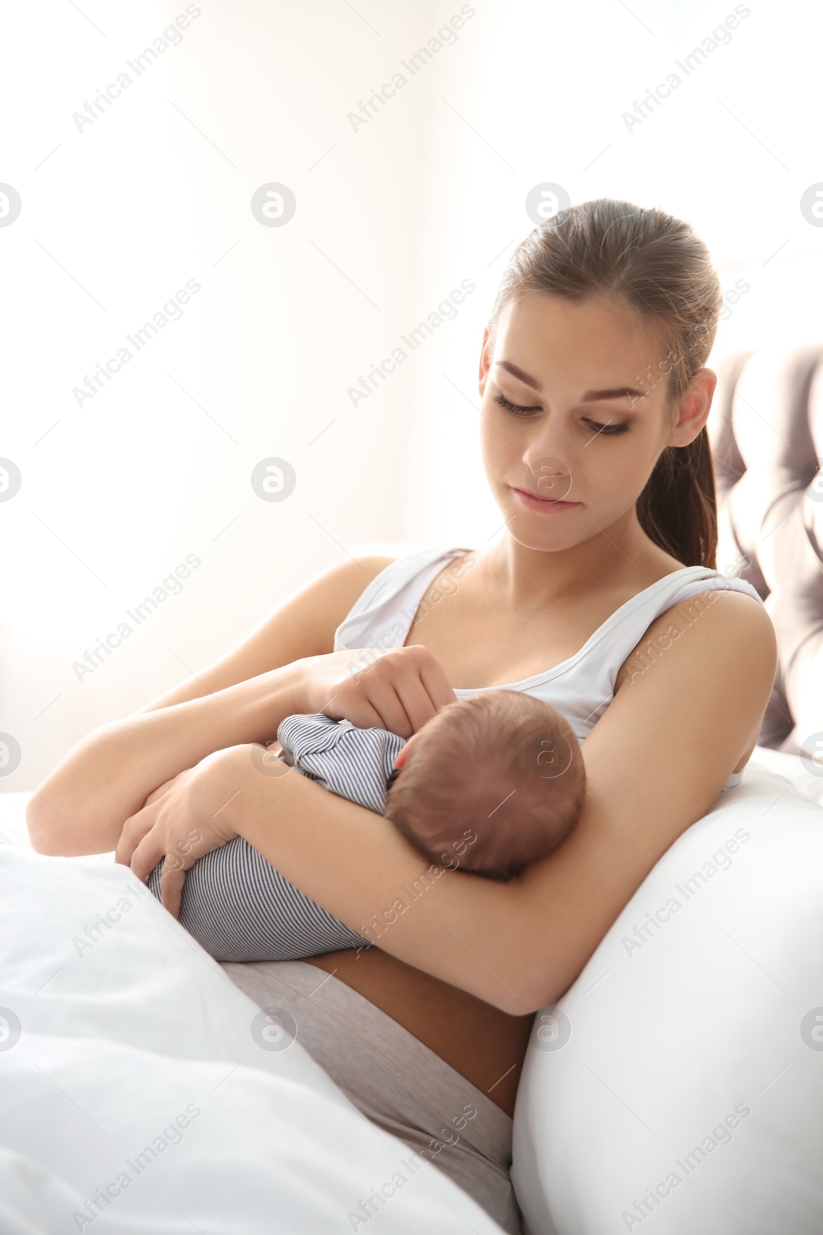 Photo of Young woman breastfeeding her baby in bedroom