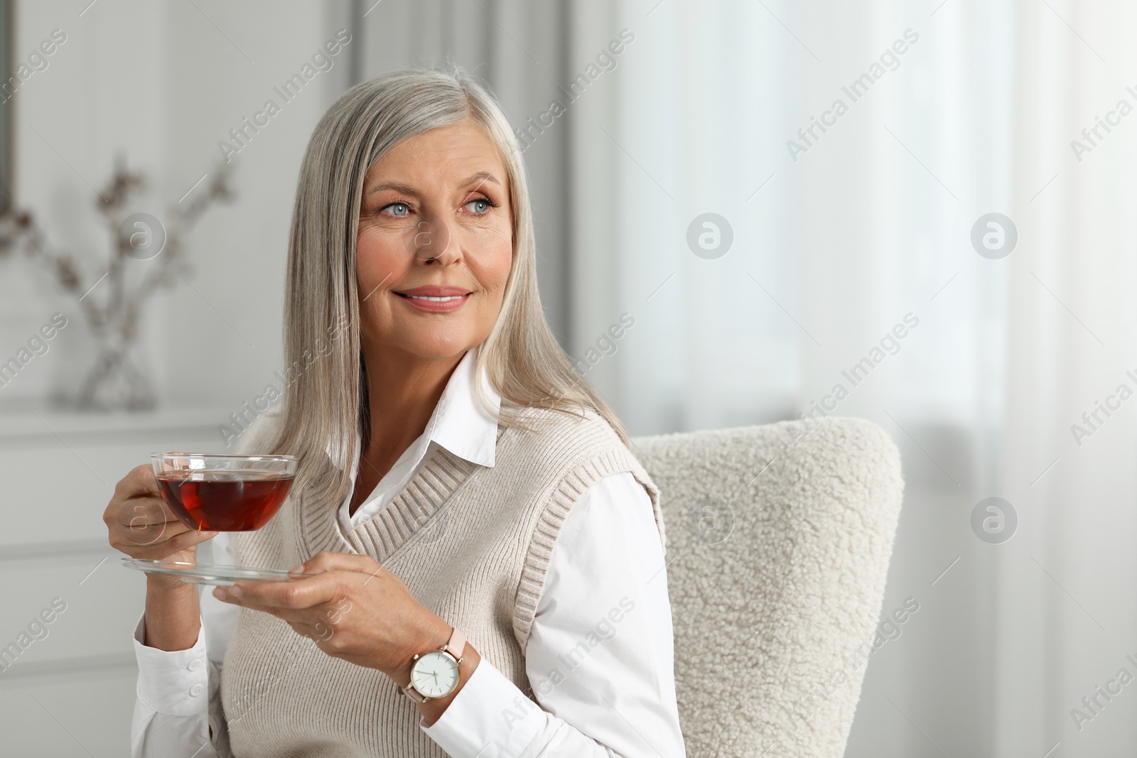 Photo of Portrait of beautiful middle aged woman with cup of tea at home, space for text