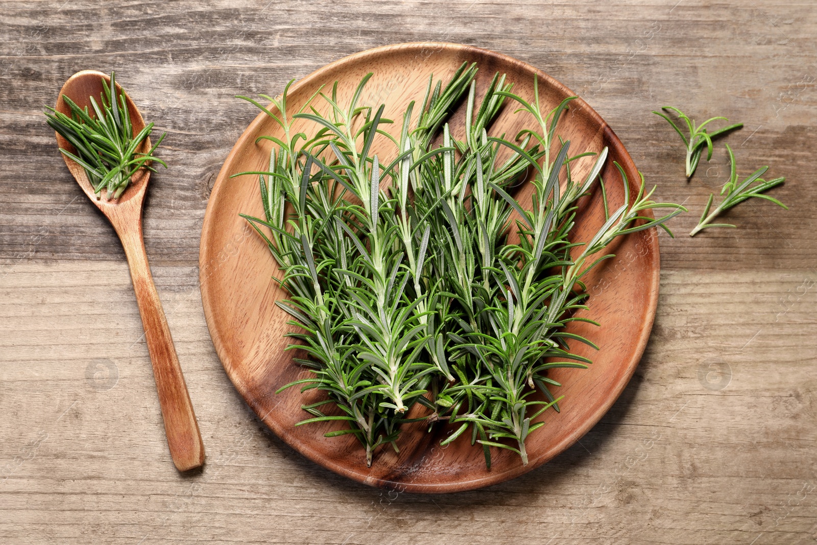 Photo of Fresh rosemary sprigs on wooden table, flat lay