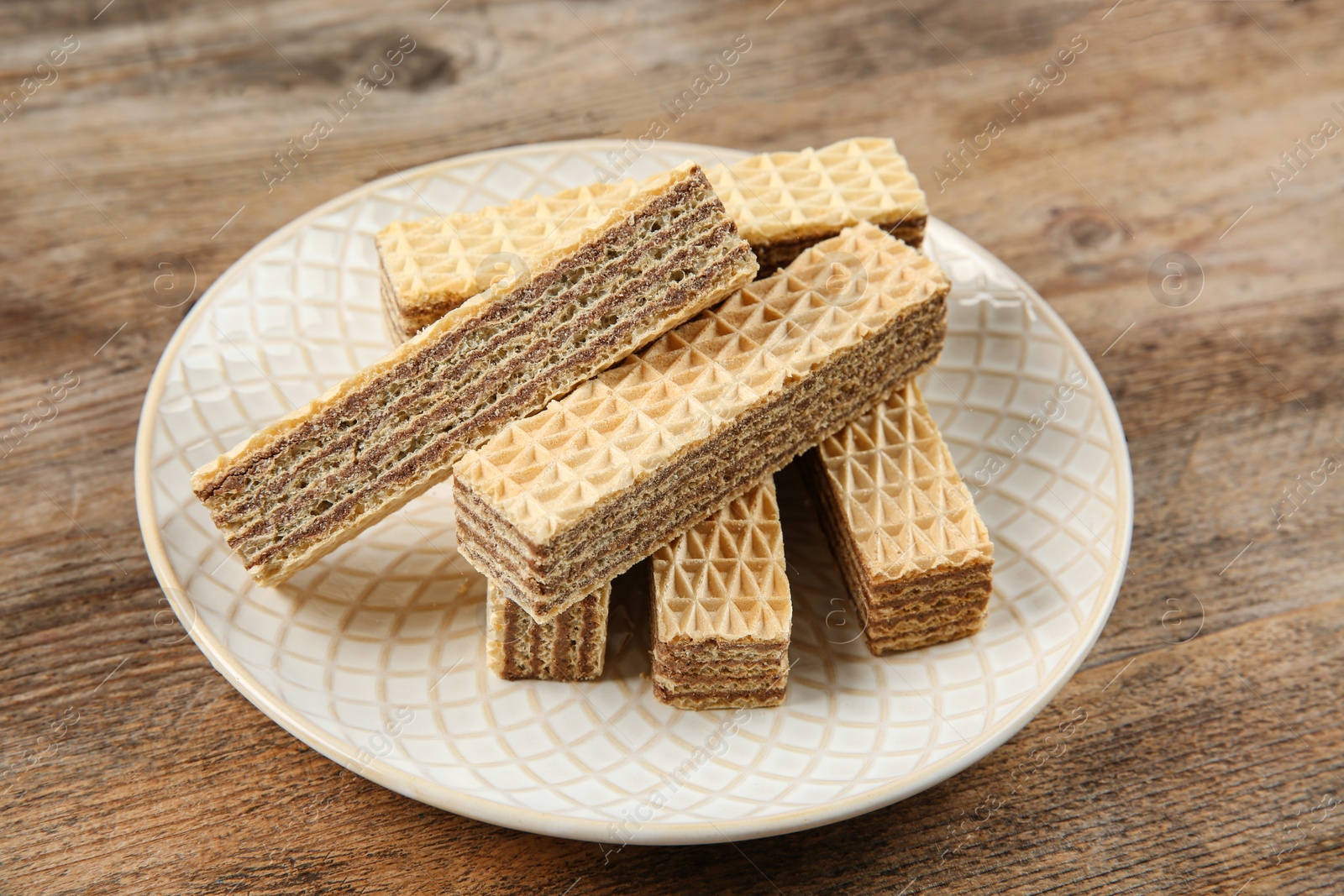 Photo of Plate of delicious wafers on brown wooden background