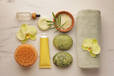 Photo of Flat lay composition with spa products and beautiful flowers on white marble table