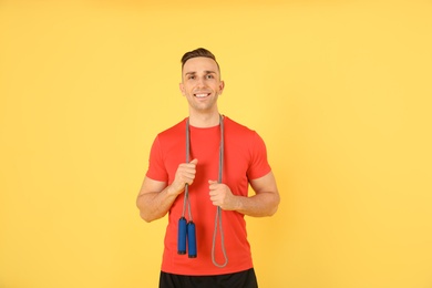 Photo of Portrait of young sportive man with jump rope on color background