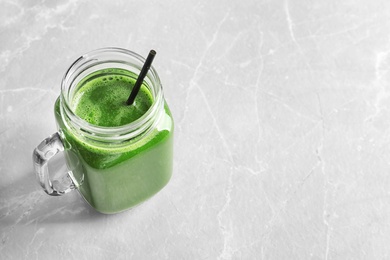 Photo of Mason jar with delicious detox juice on light background