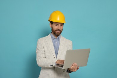 Photo of Professional engineer in hard hat with laptop on light blue background
