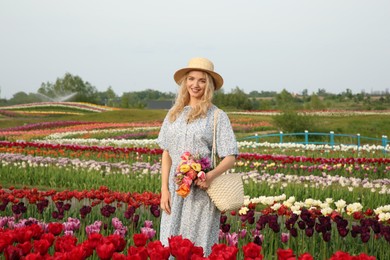 Woman with bag of spring flowers in beautiful tulip field