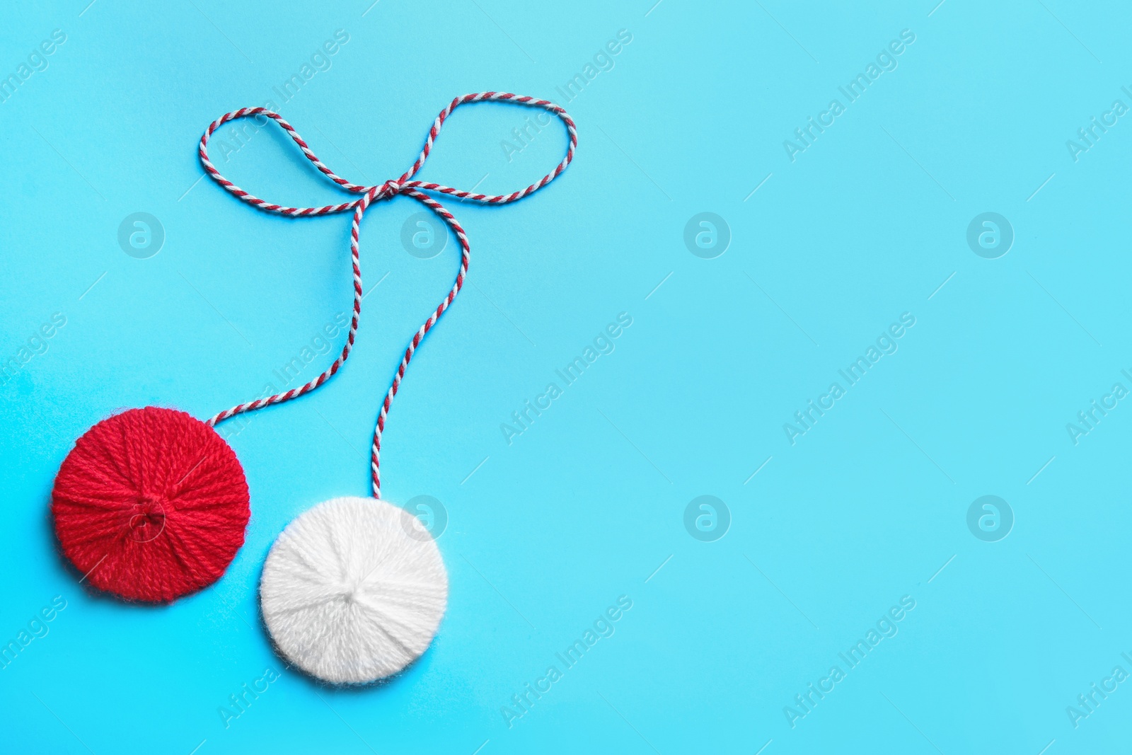 Photo of Traditional martisor on light blue background, top view with space for text. Beginning of spring celebration