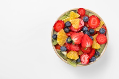 Yummy fruit salad in bowl on light blue background, top view. Space for text