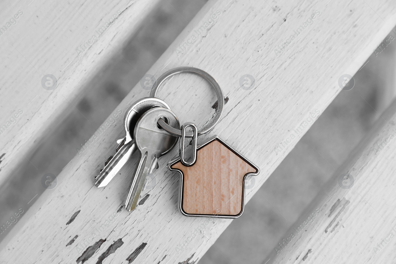 Photo of Keys with trinket in shape of house on wooden surface, top view. Real estate agent services