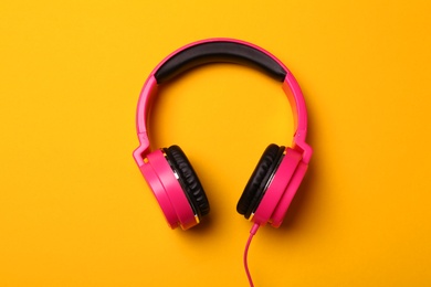 Stylish modern headphones on color background, top view