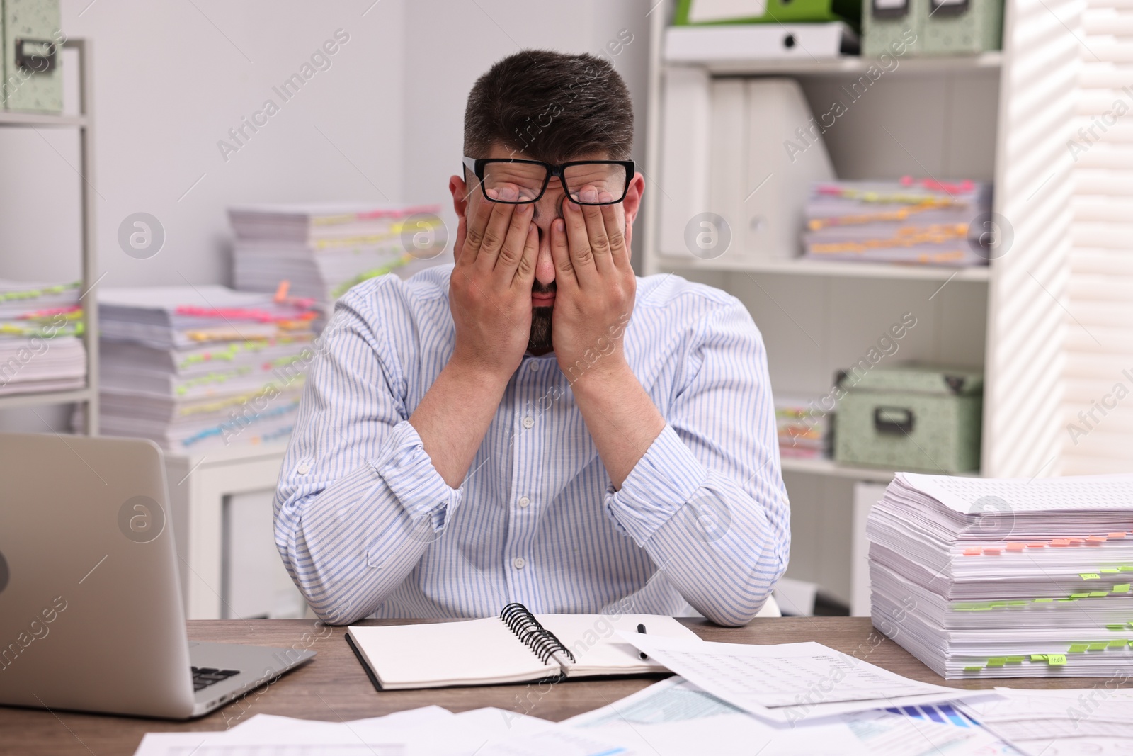 Photo of Overwhelmed man sitting at table in office