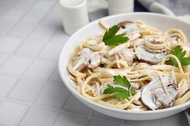 Photo of Delicious pasta with mushrooms on white tiled table, closeup