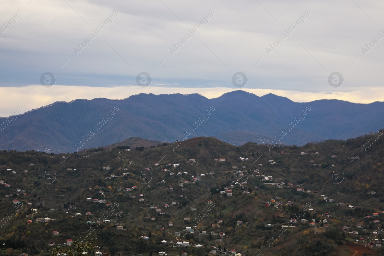 Photo of Cloudy sky over mountain valley with houses. Picturesque view