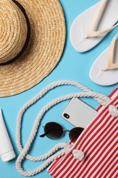 Photo of Flat lay composition with bag and other beach accessories on light blue background