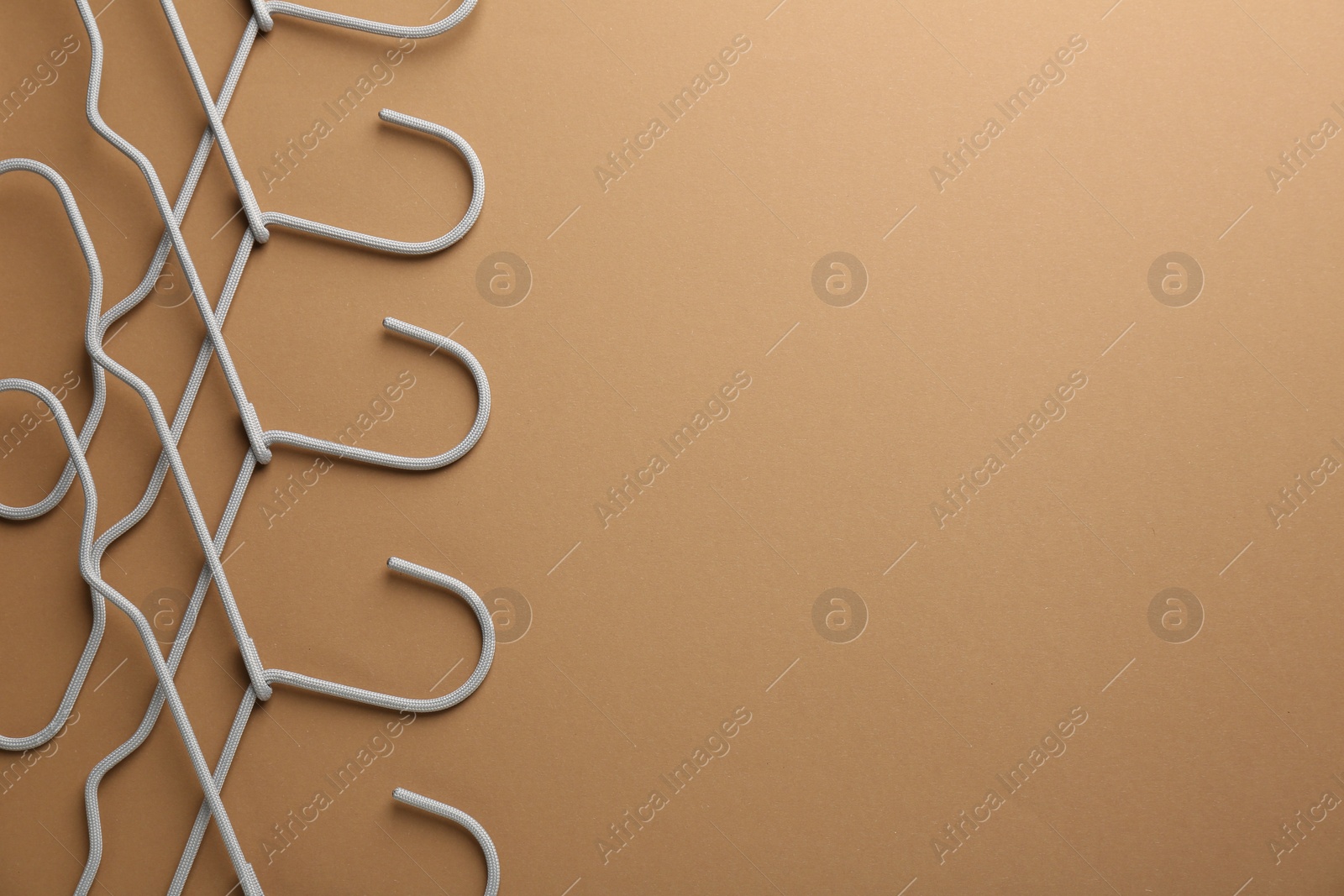 Photo of Empty hangers on brown background, top view. Space for text