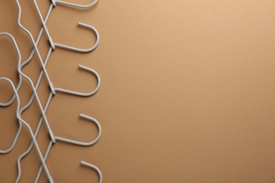 Photo of Empty hangers on brown background, top view. Space for text