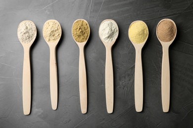 Photo of Spoons with different types of flour on grey background, top view