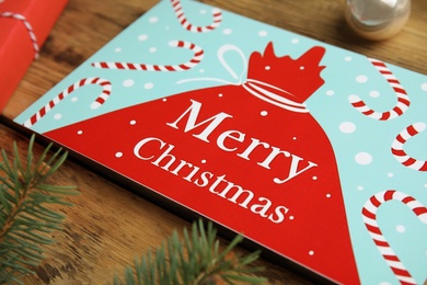 Photo of Christmas card and fir branches on wooden background, closeup