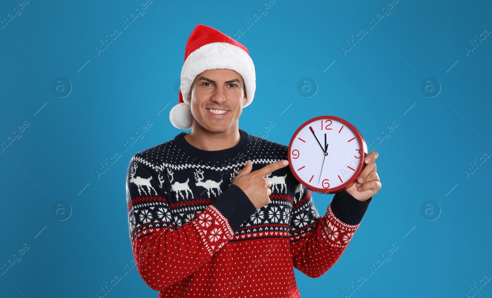 Photo of Man in Santa hat with clock on blue background. New Year countdown