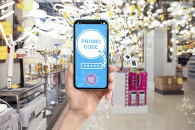 Woman holding smartphone with activated promo code in shopping mall, closeup